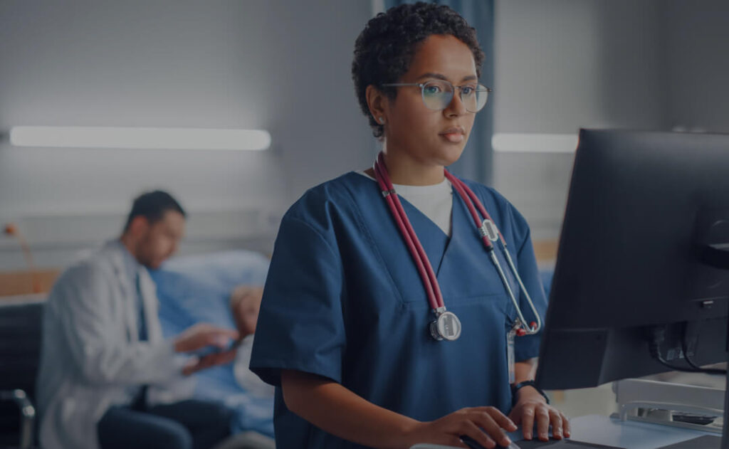 A healthcare professional in scrubs using her workstation to create a discharge plan with the Qventus inpatient solution